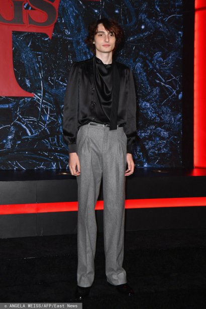 Finn Wolfhard  w czarnej satynowej koszuli i spodniach na kant.