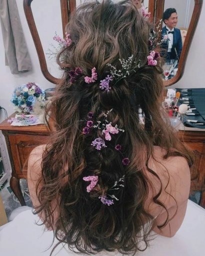 Fryzura w stylu boho z ozdobą w postaci fioletowych kwiatków.