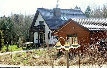 Dom Zbigniewa Ziobry ma prostą bryłę i jest zbudowany na planie prostokąta. Dom ma białe ściany i czarny dach.